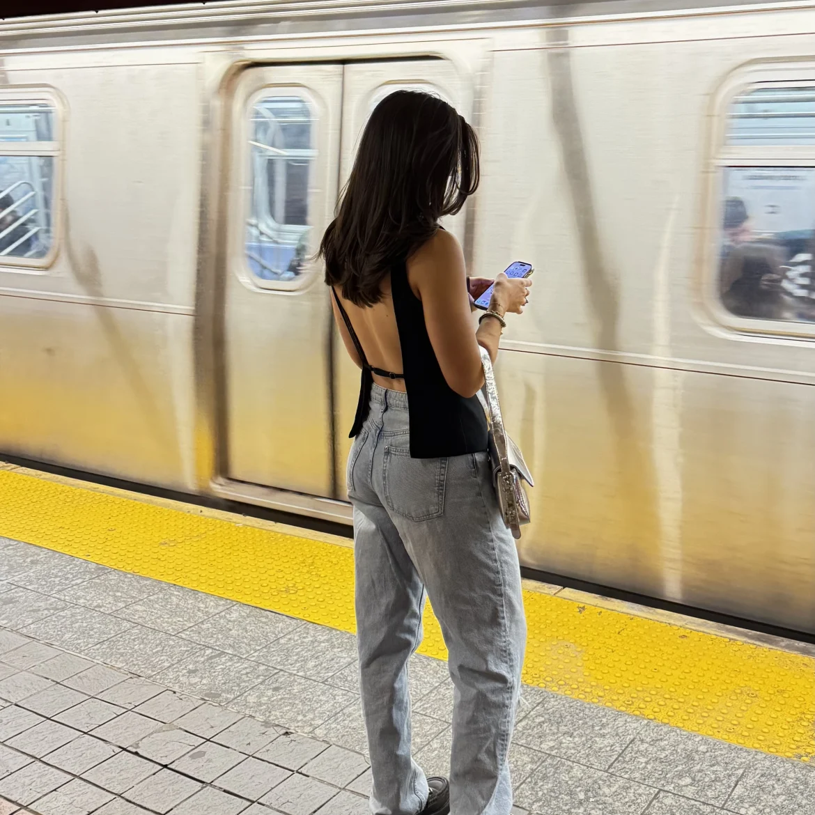 Vrouw bij metro met telefoon in hand