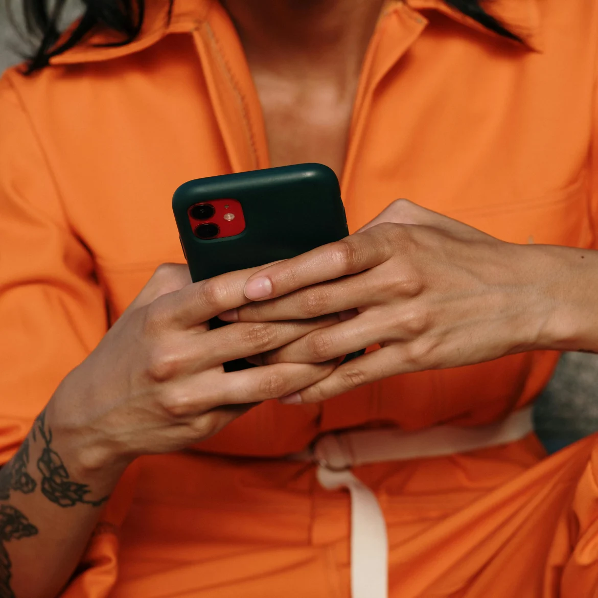 Vrouw met telefoon in hand in oranje kleding