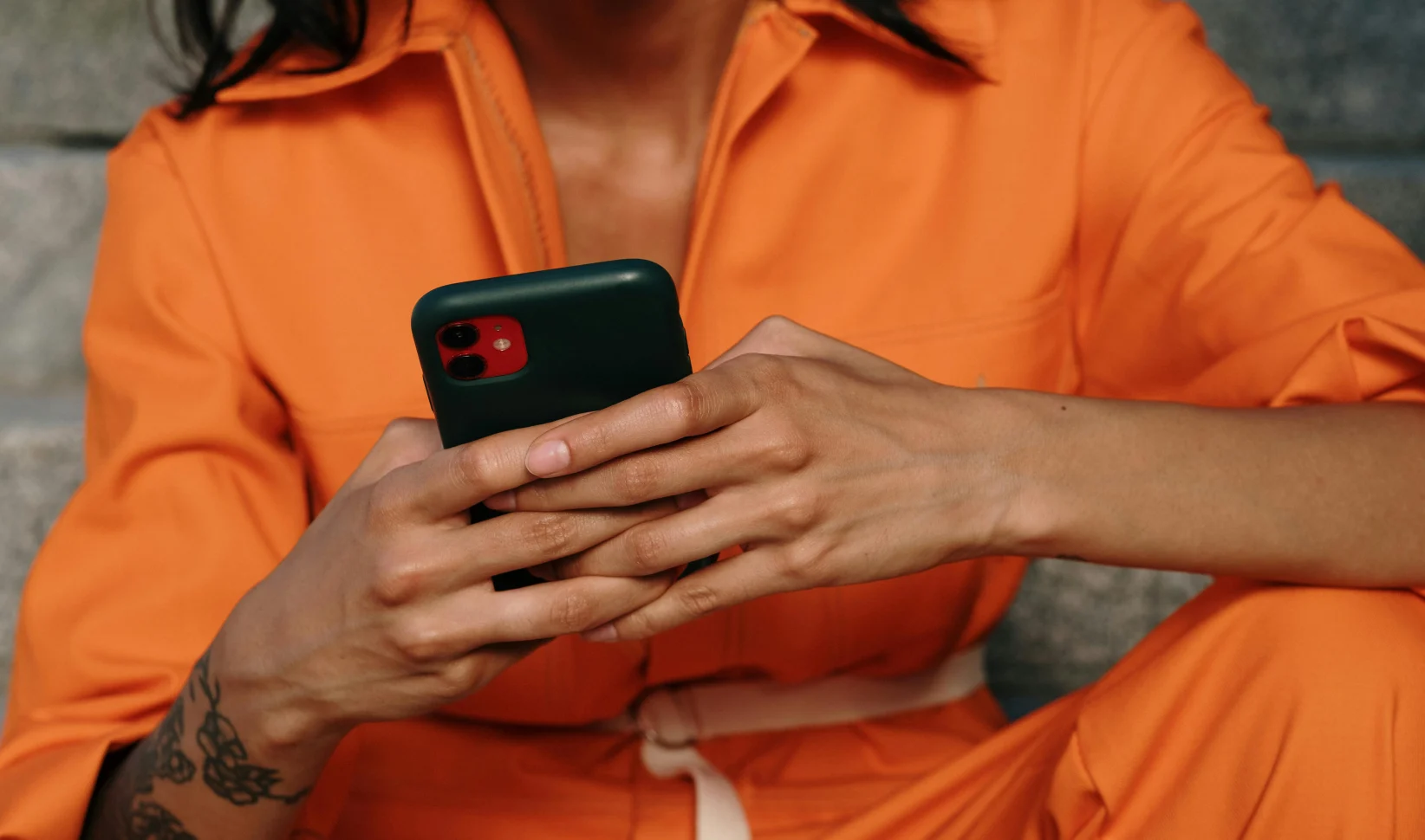 Vrouw met telefoon in hand in oranje kleding