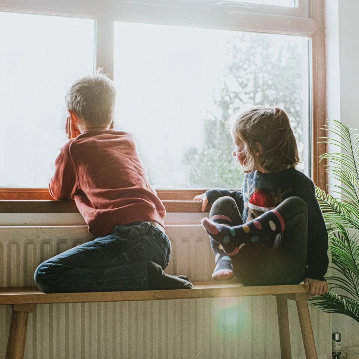 Twee kinderen in armoede zitten voor het raam tijdens de zomervakantie