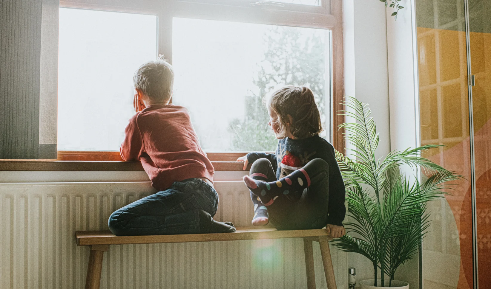 Twee kinderen in armoede zitten voor het raam tijdens de zomervakantie