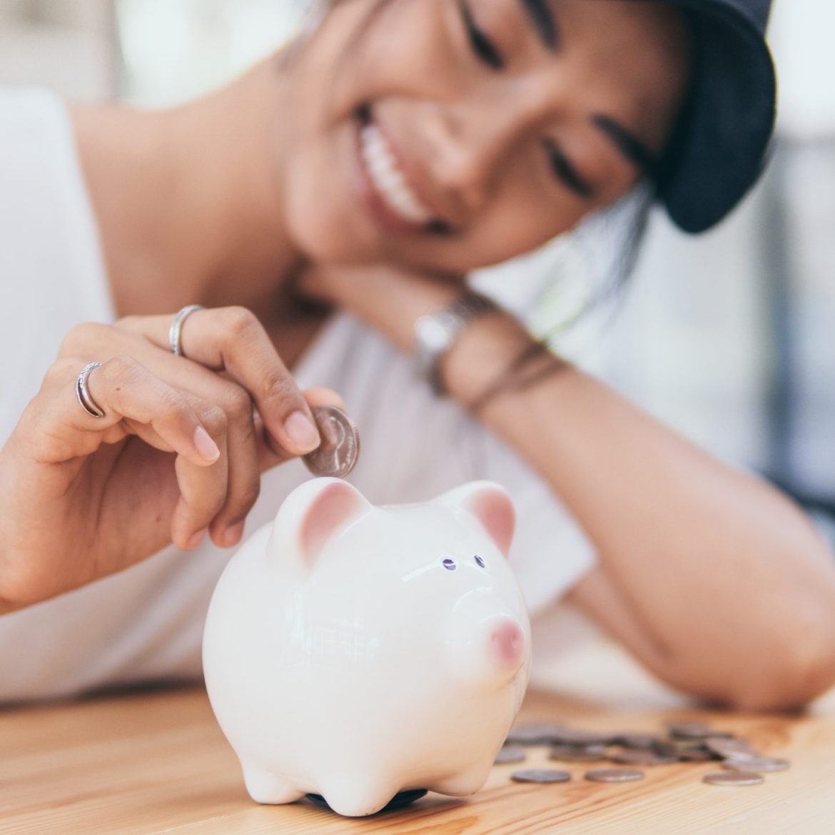 Lachende vrouw die geld in spaarpot stopt