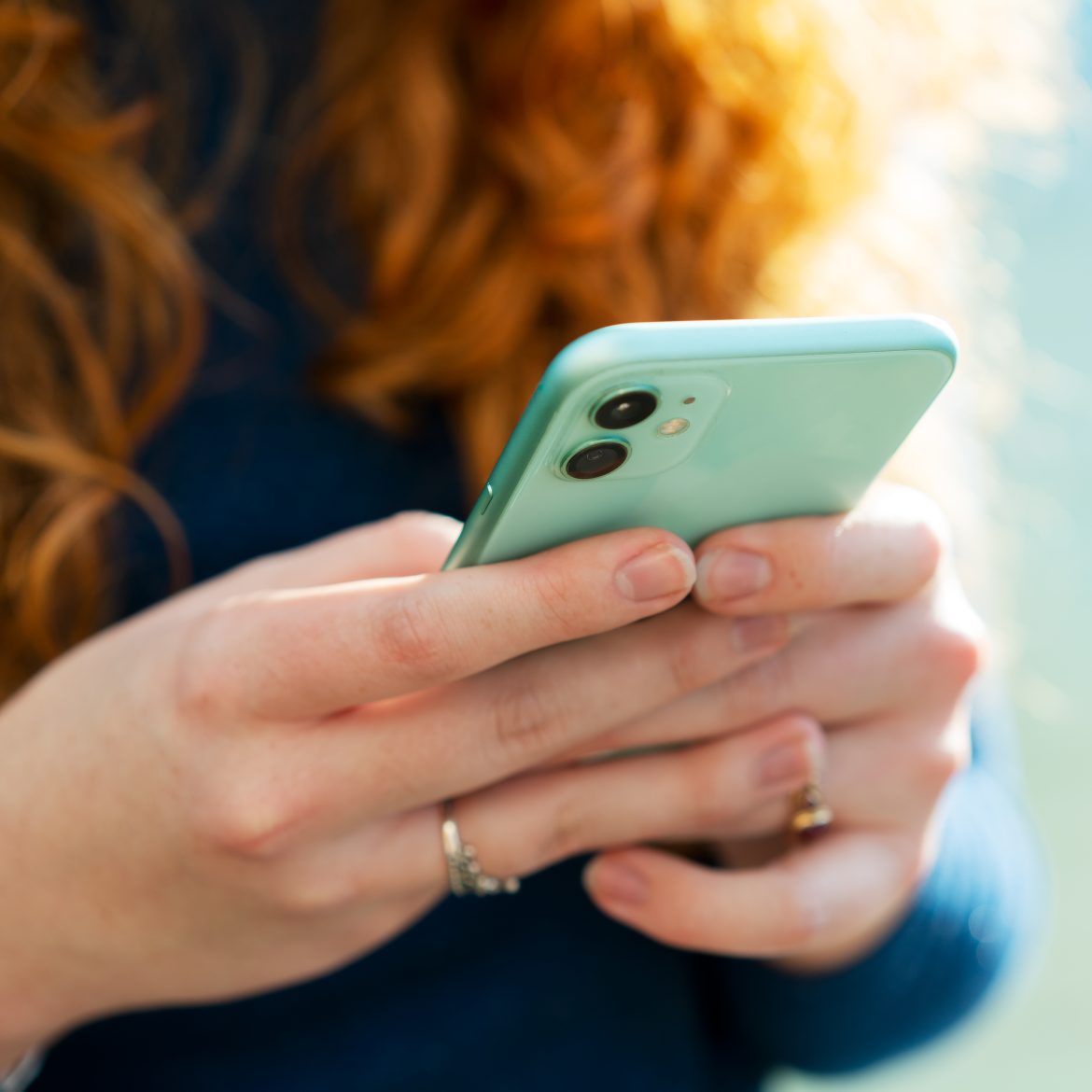 vrouw met rood haar met een groene telefoon in haar handen