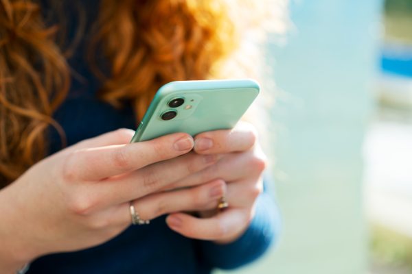 vrouw met rood haar met een groene telefoon in haar handen