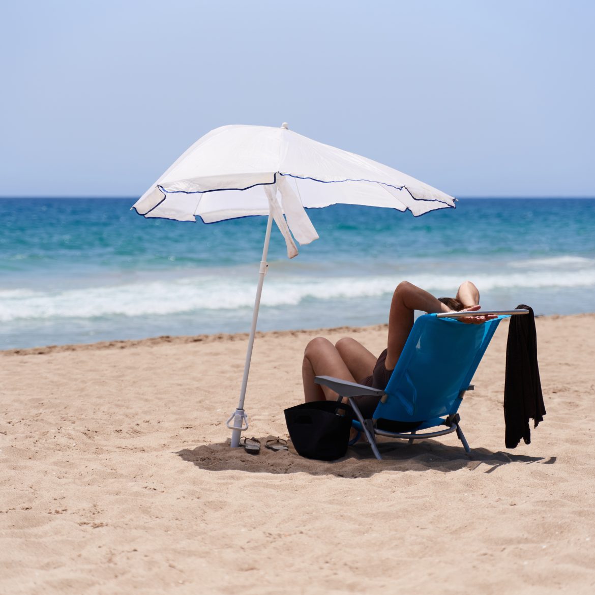 Vrouw in een stoel op het strand met parasol