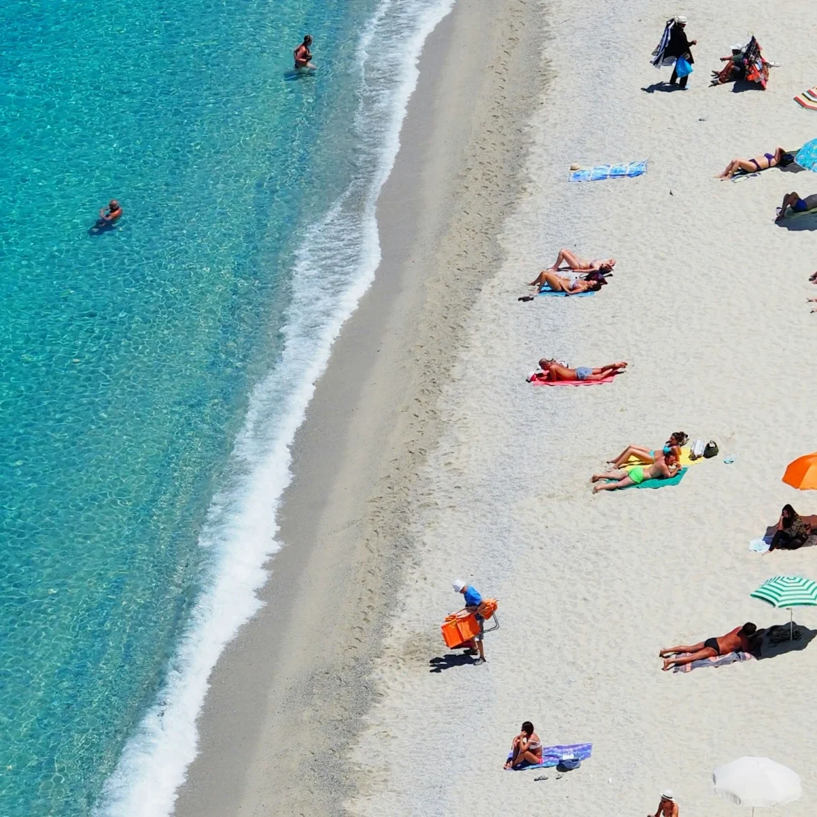 Wit strand, blauwe zee en parasols.