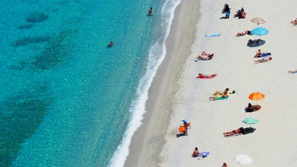 Wit strand, blauwe zee en parasols.