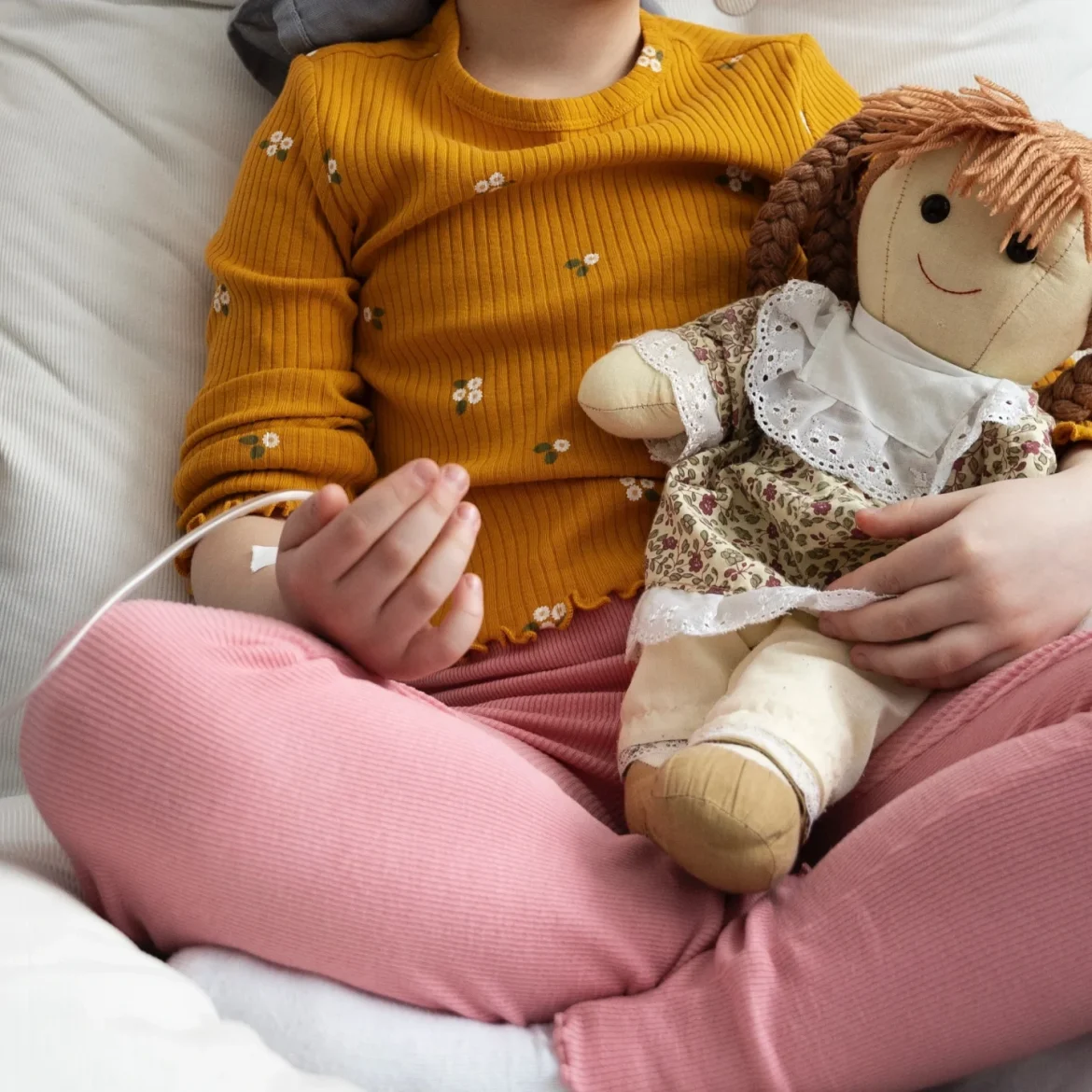 Ziek meisje op ziekenhuisbed met knuffel in haar handen