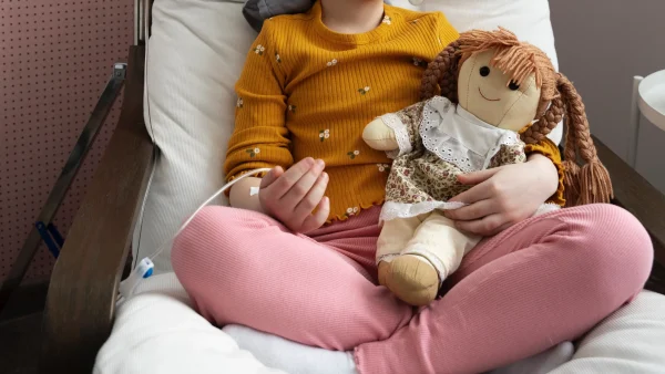 Ziek meisje op ziekenhuisbed met knuffel in haar handen
