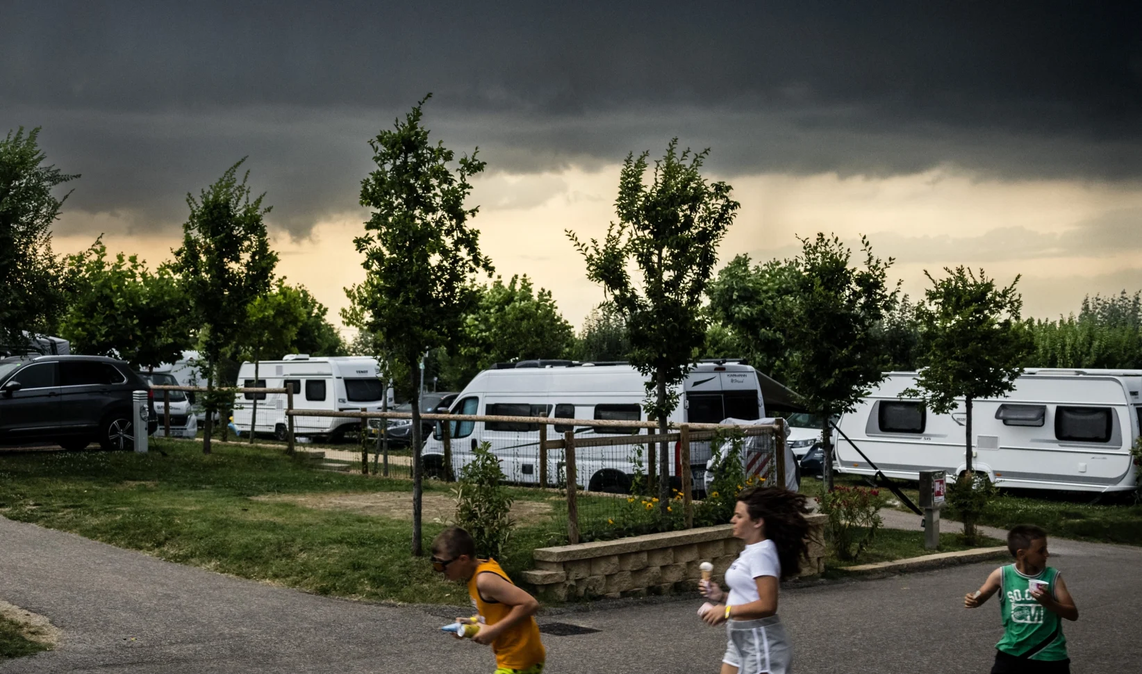 Noodweer verwacht Alpen Italië Zwitserland Oostenrijk kinderen rennen donkere wolken camping