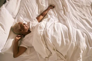 vrouw vrolijk in bed dankzij tips tegen plaknacht