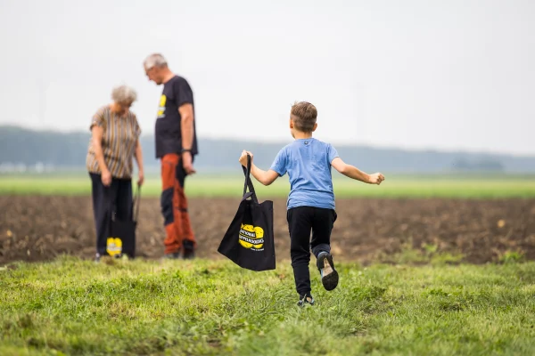 Kind loopt met tasje door de velden op aardappelrooidag
