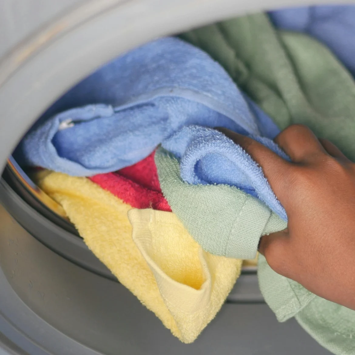 Hand pakt handdoeken uit wasmachine