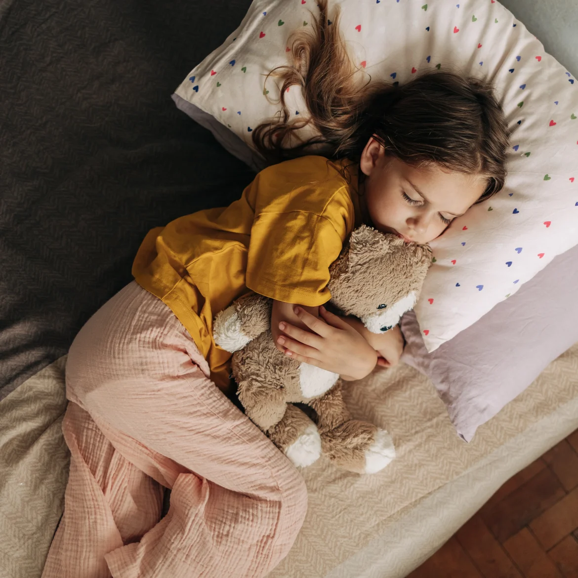 Kind ligt in bed met haar knuffel, ze heeft een samengesteld gezin
