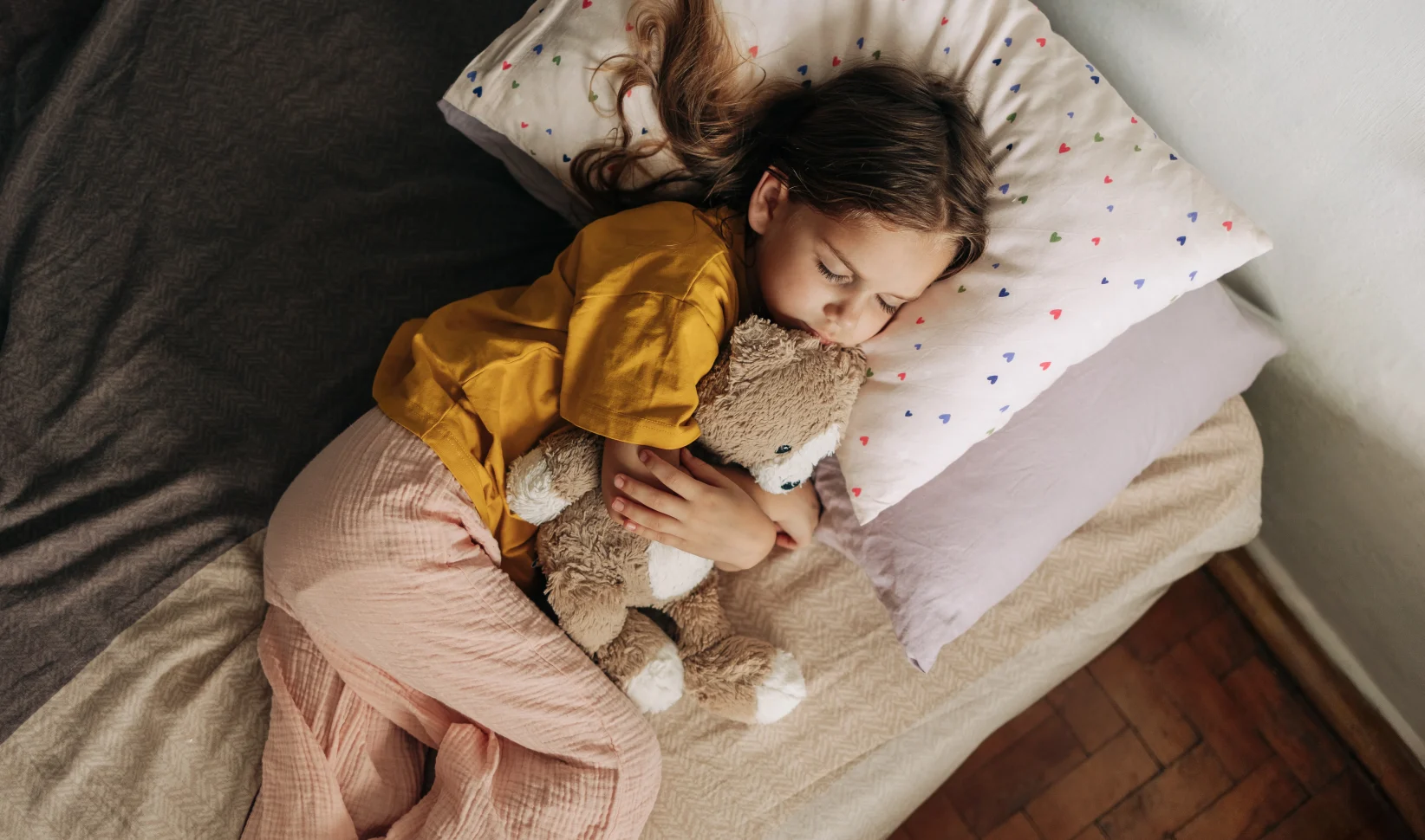 Kind ligt in bed met haar knuffel, ze heeft een samengesteld gezin