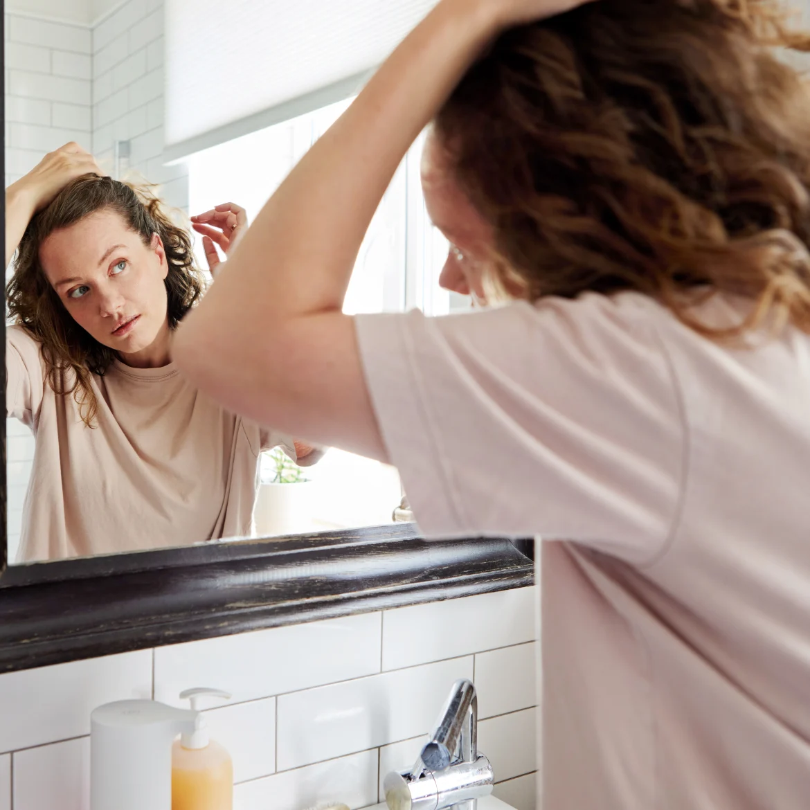 Vrouw voor de spiegel die grijze haren uittrekt
