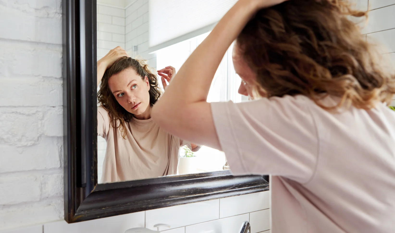 Vrouw voor de spiegel die grijze haren uittrekt