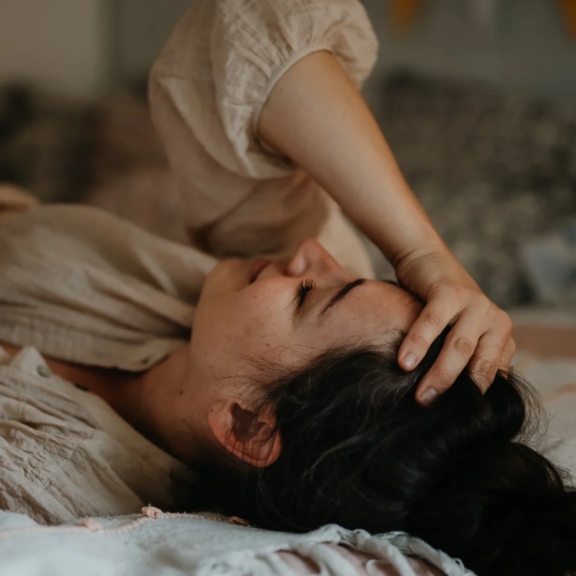 Slaapverlamming, illustratief beeld van een vrouw die in bed ligt met een hand op haar hoofd.