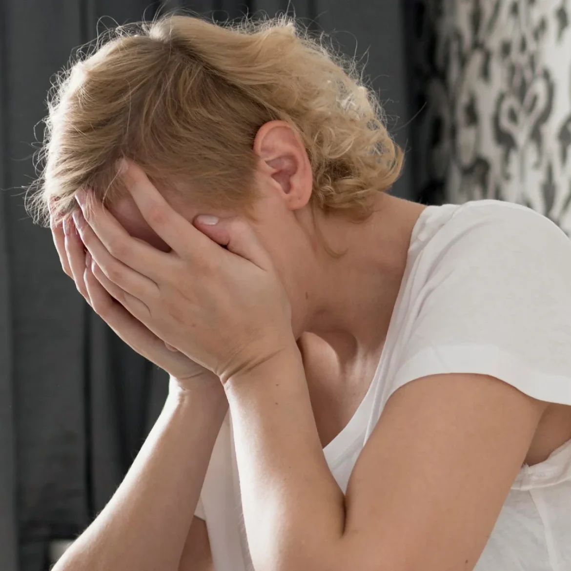 Vrouw baalt met haar handen voor haar gezicht want haar stiefkinderen komen slapen en dan gaat het mis