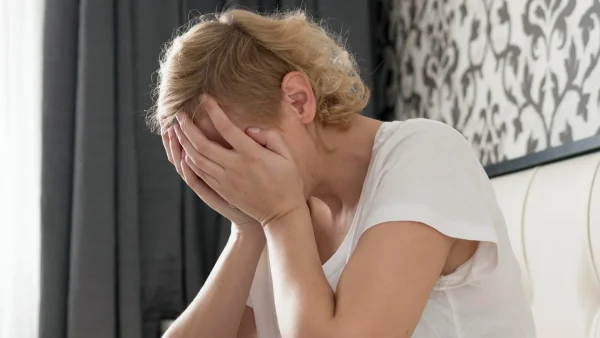 Vrouw baalt met haar handen voor haar gezicht want haar stiefkinderen komen slapen en dan gaat het mis