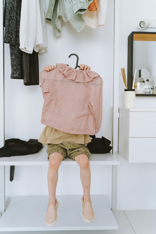 Kind heeft hanger met kleding vast.