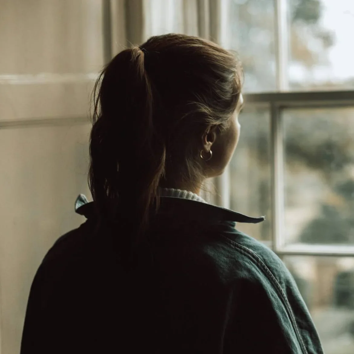 Jongere vrouw kijkt uit raam