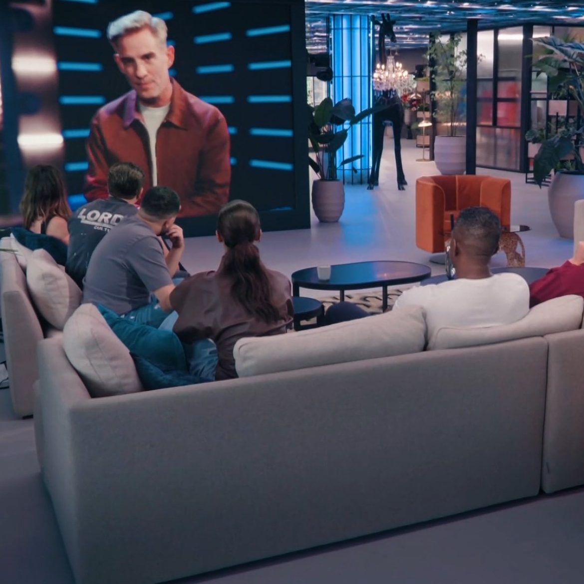 Alle BN'ers zitten op de bank en kijken naar Art Rooijakkers in 'Het zwaard van Damocles'