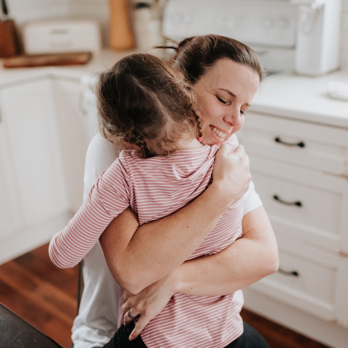 Kind geeft moeder een knuffel in de keuken