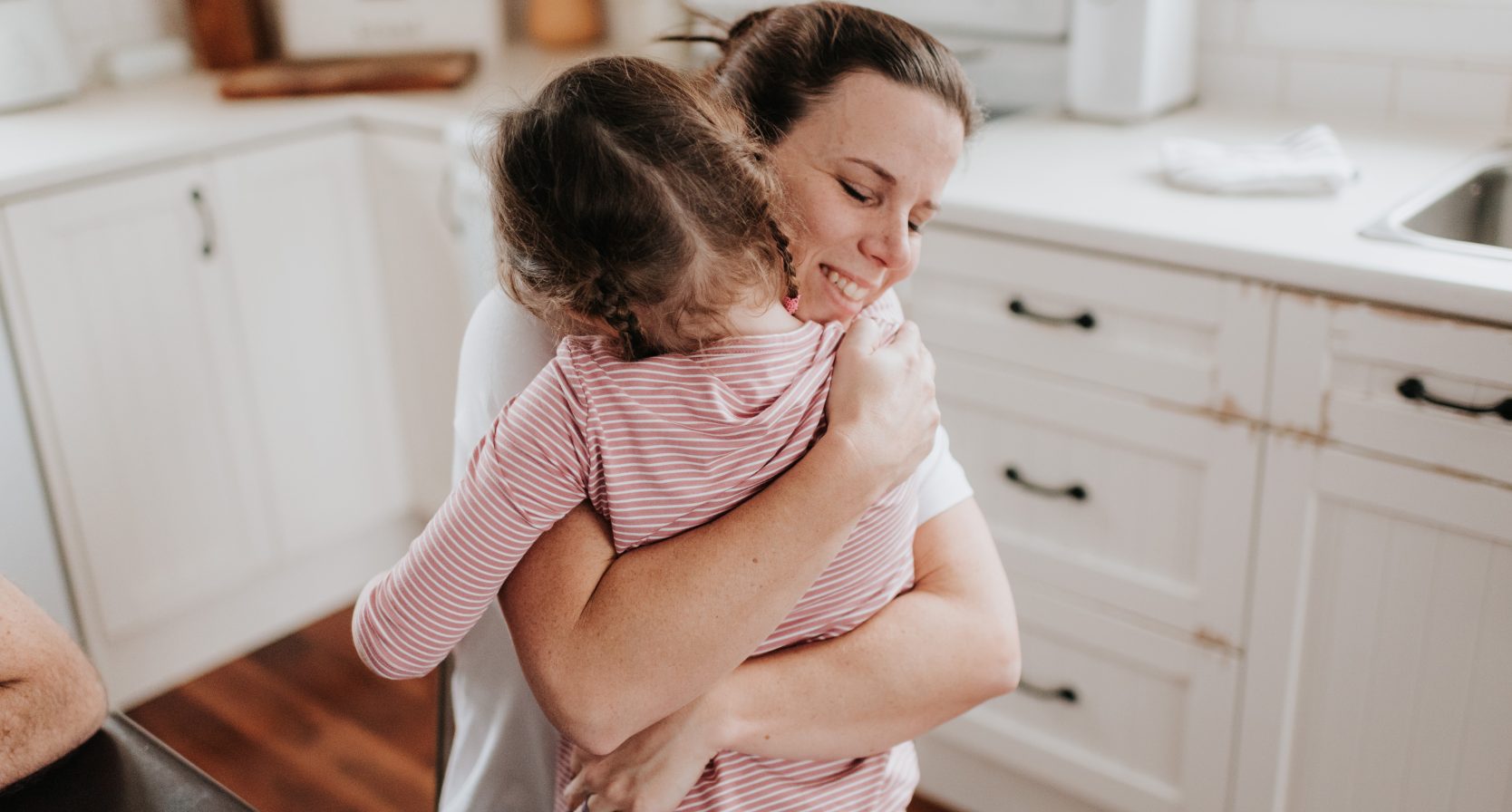 Kind geeft moeder een knuffel in de keuken