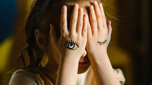 Kind bedekt gezicht met handen