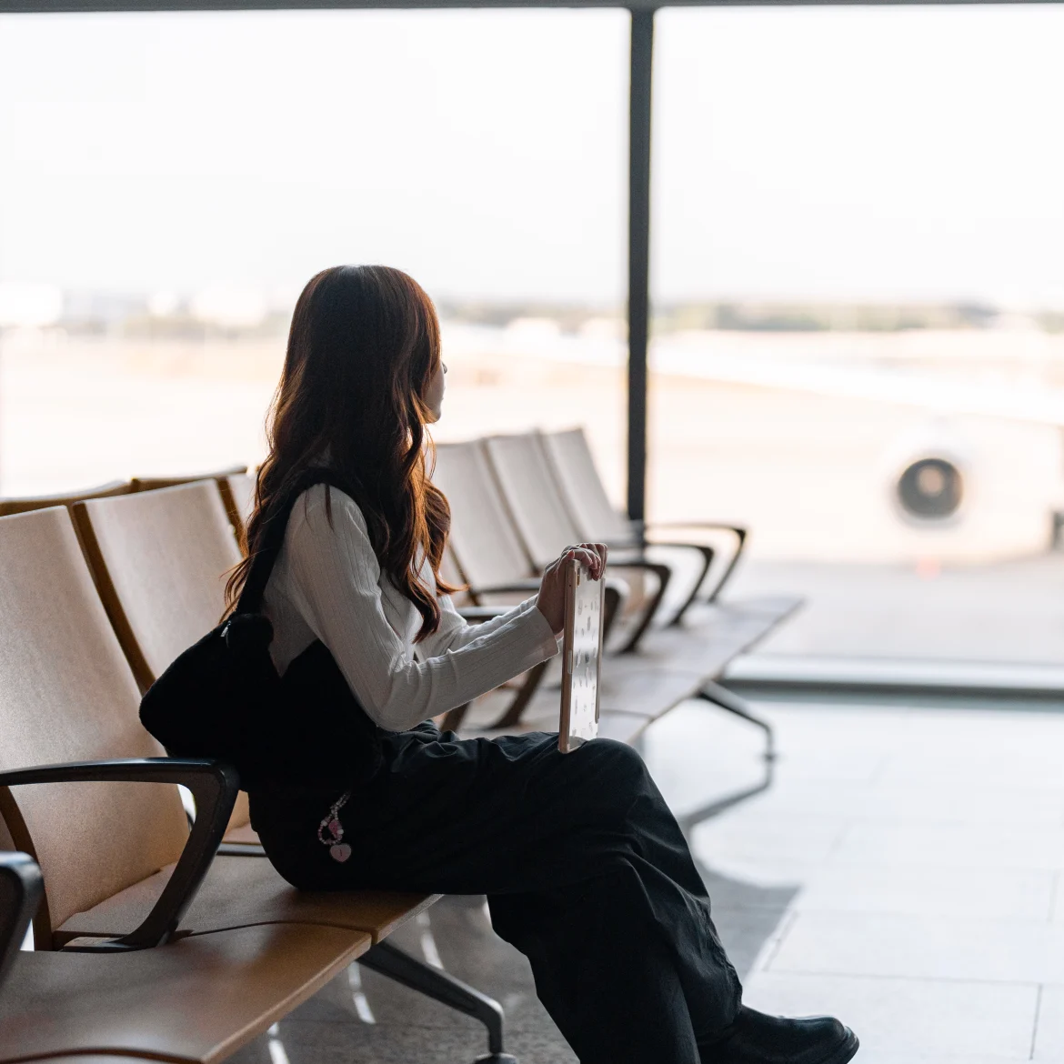 Vriend verhuizen naar buitenland verhaal, illustratief beeld van een vrouw wachtend op een vliegveld