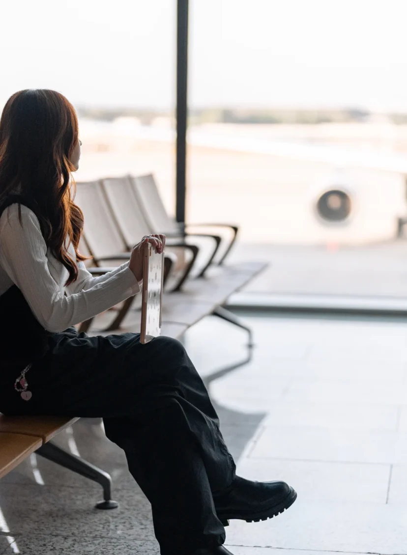 Vriend verhuizen naar buitenland verhaal, illustratief beeld van een vrouw wachtend op een vliegveld