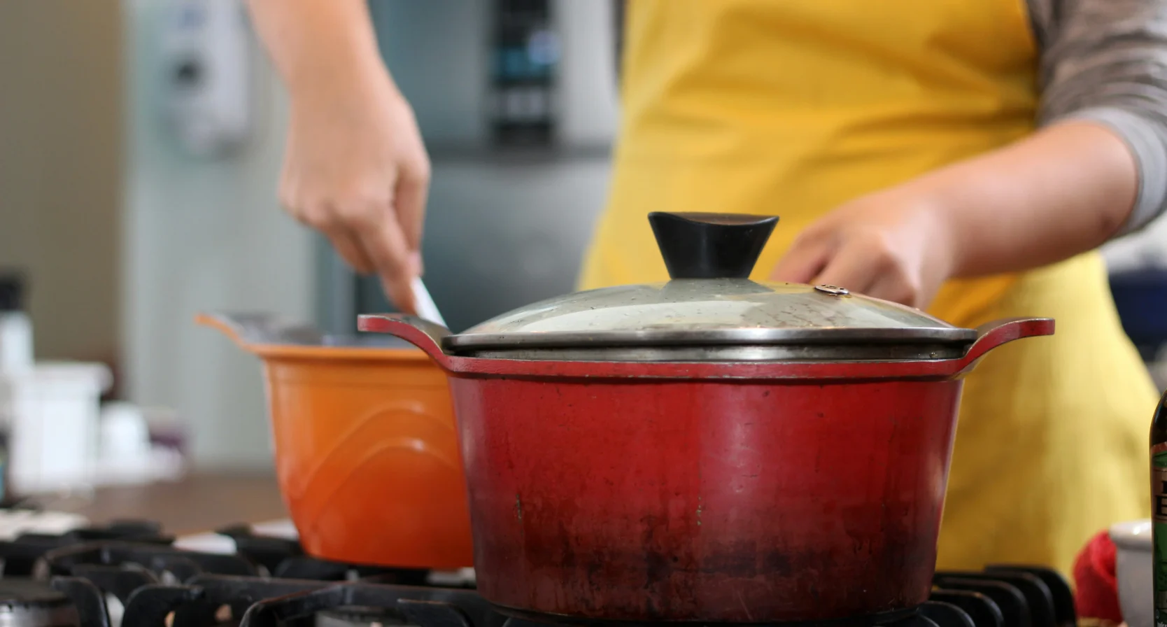 Vrouw kookt, de deksel zit op de pan zoals de bemoeiende buurman graag wil