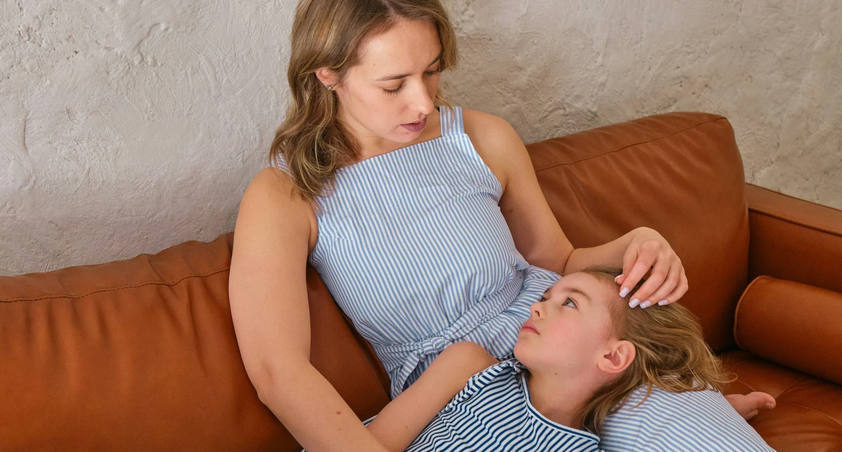 Dochter ligt op de schoot van moeder op de bank, ze is verdrietig om haar stiefzussen