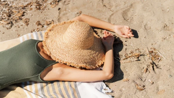 Vrouw viel in slaap op vakantie in de zon, illustratief beeld van een vrouw slapend op het strand