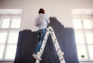 vrouw staat op trap muren te verven
