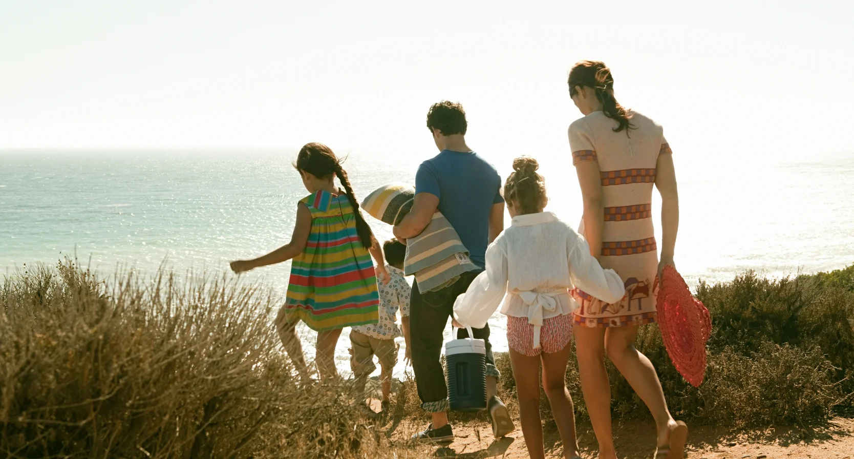 Een samengesteld gezin is op vakantie en loopt naar het strand