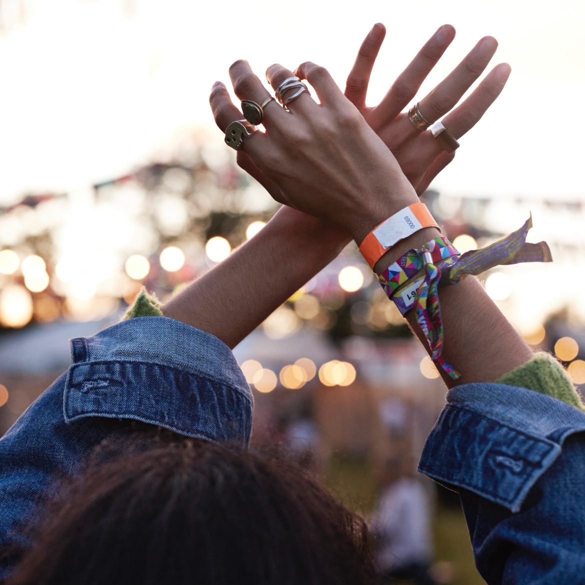 Gepest op een festival, illustratief beeld van een vrouw die haar handen omhoog doet met festivalbandjes