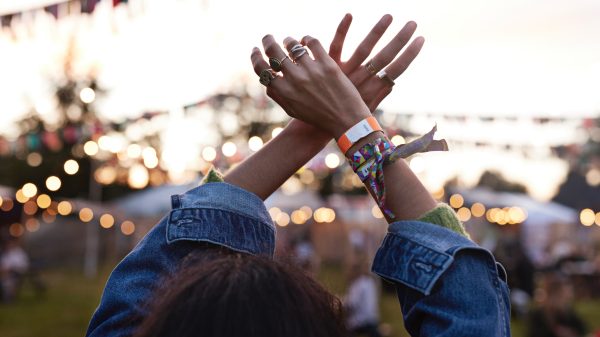 Gepest op een festival, illustratief beeld van een vrouw die haar handen omhoog doet met festivalbandjes