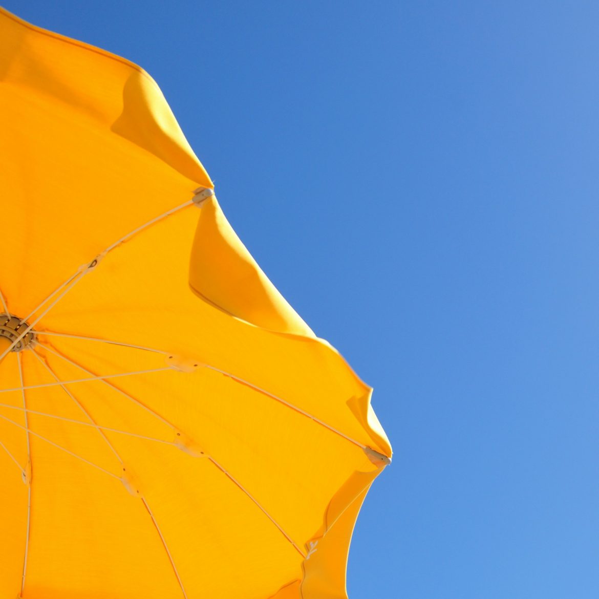 Tropische temperaturen dit weekend, illustratief beeld van twee parasols in de blauwe lucht
