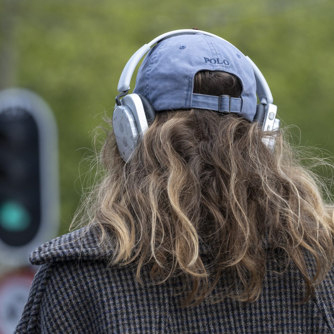 Vrouw met koptelefoon. in het verkeer. Stoplicht staat op groen.