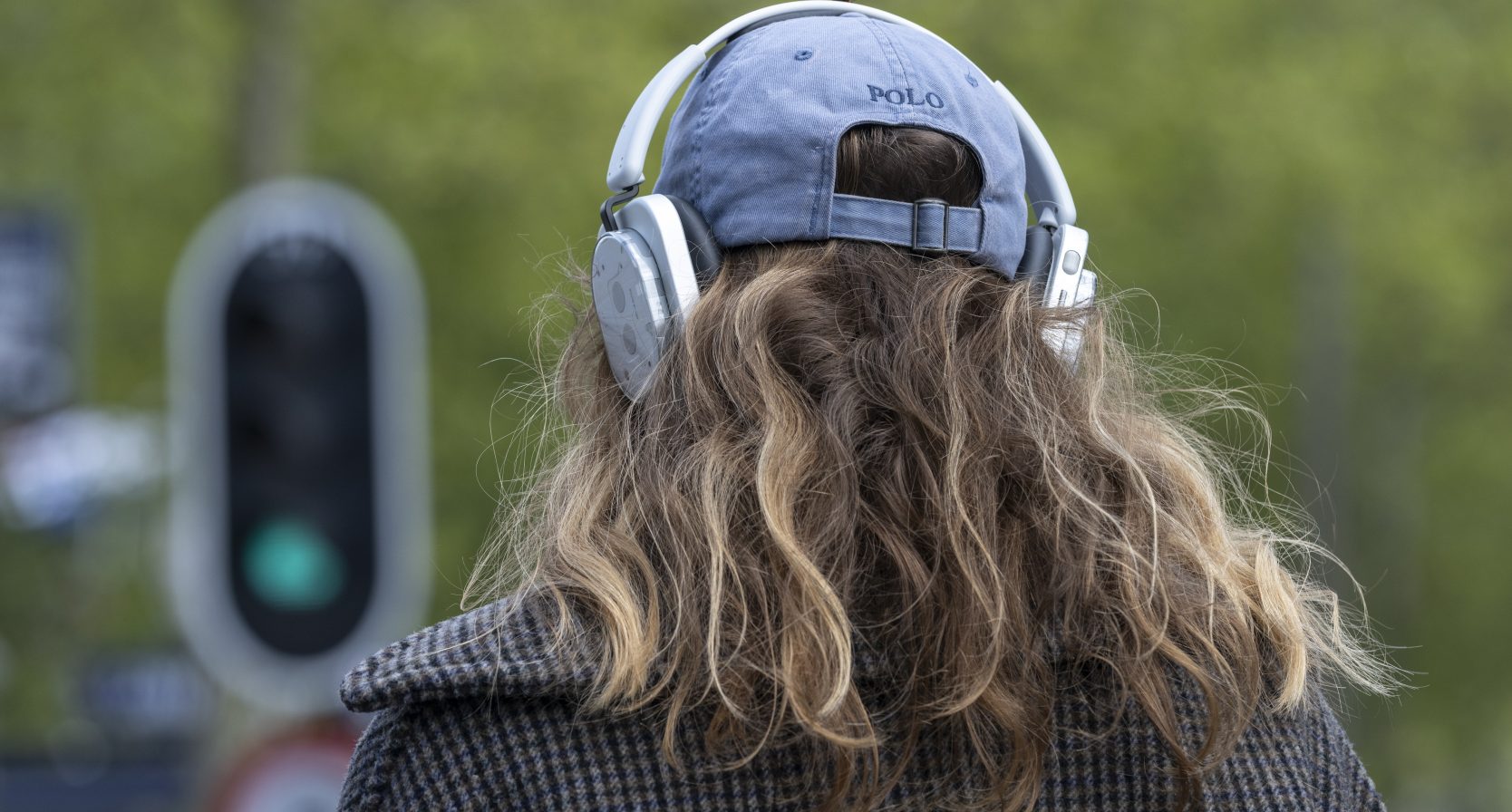 Vrouw met koptelefoon. in het verkeer. Stoplicht staat op groen.