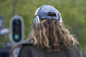 Vrouw met koptelefoon. in het verkeer. Stoplicht staat op groen.