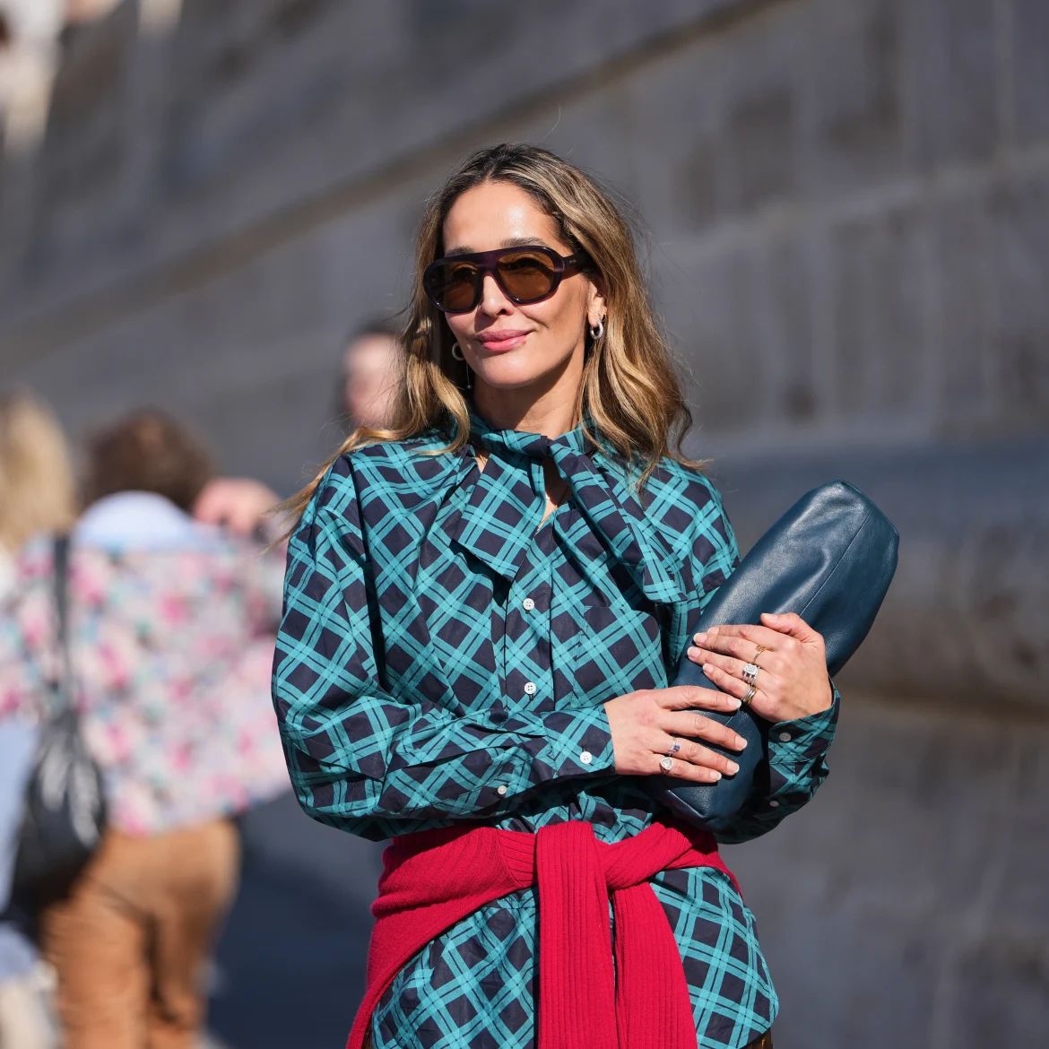 Vrouw met rode trui over blauwe blouse geknoopt