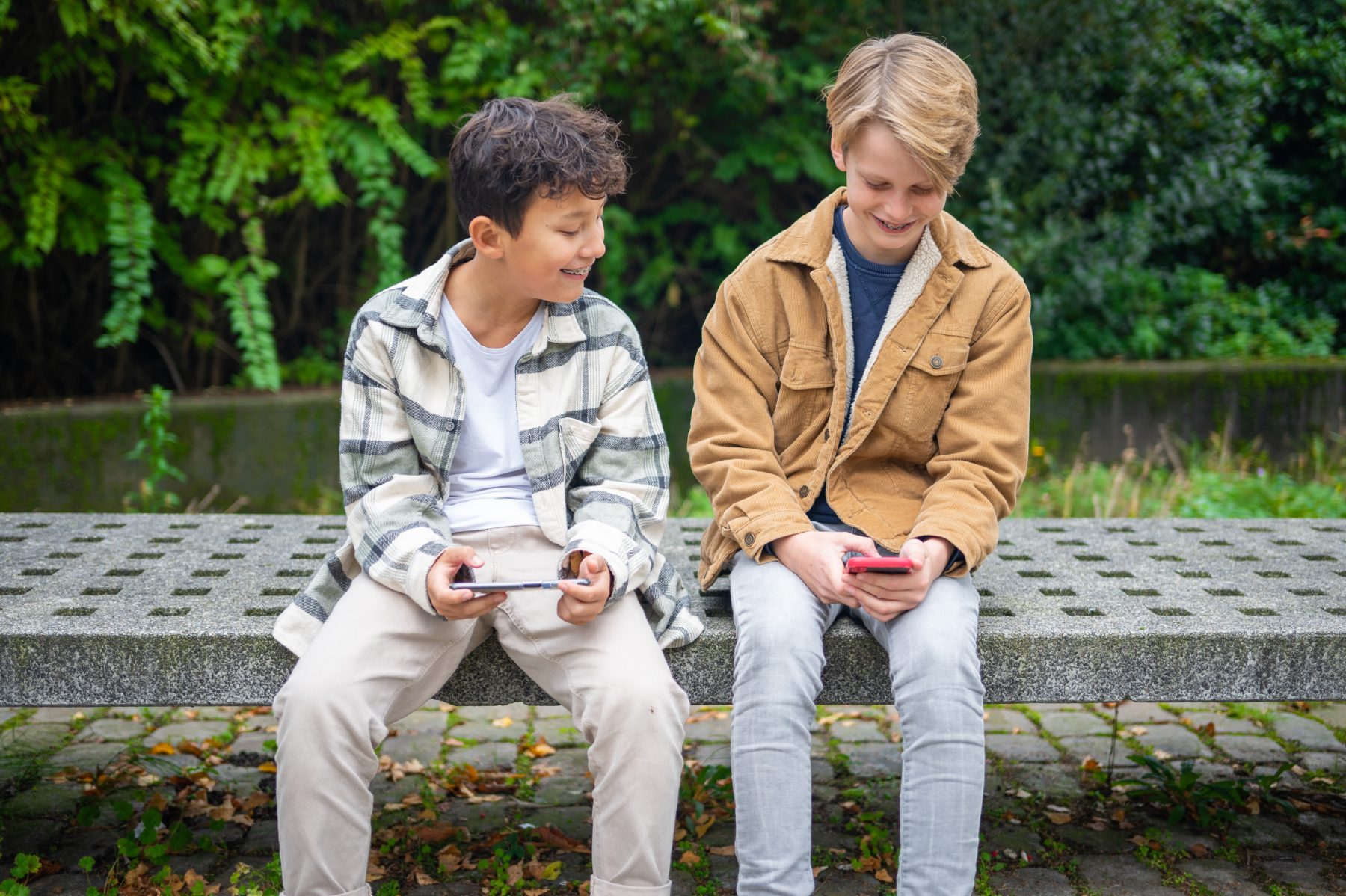 Twee basisschoolkinderen met telefoons in hun handen