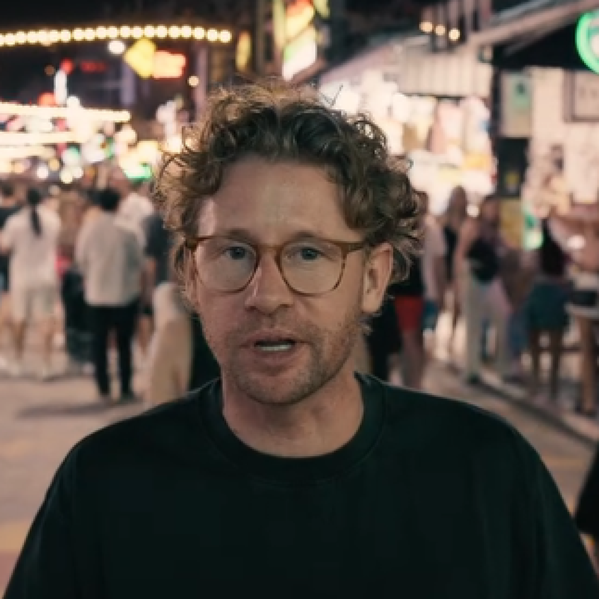 Ewout Genemans vertelt voor de camera op een drukke straat in Thailand