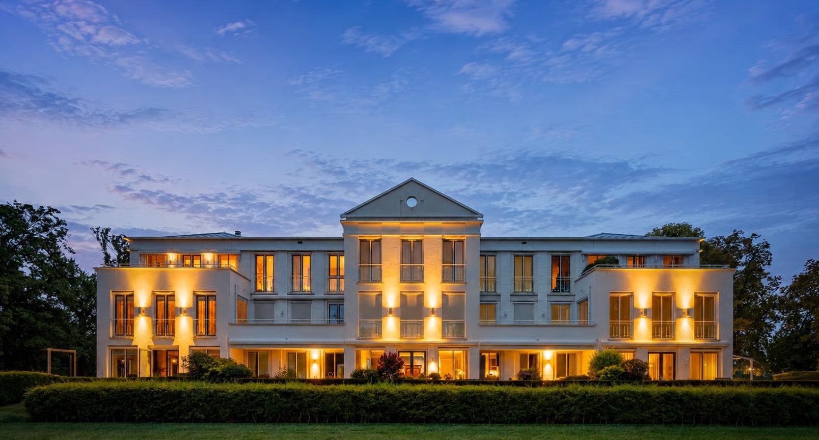 De gevel van een penthouse in Epe dat lijkt op het Witte Huis, bij schemering