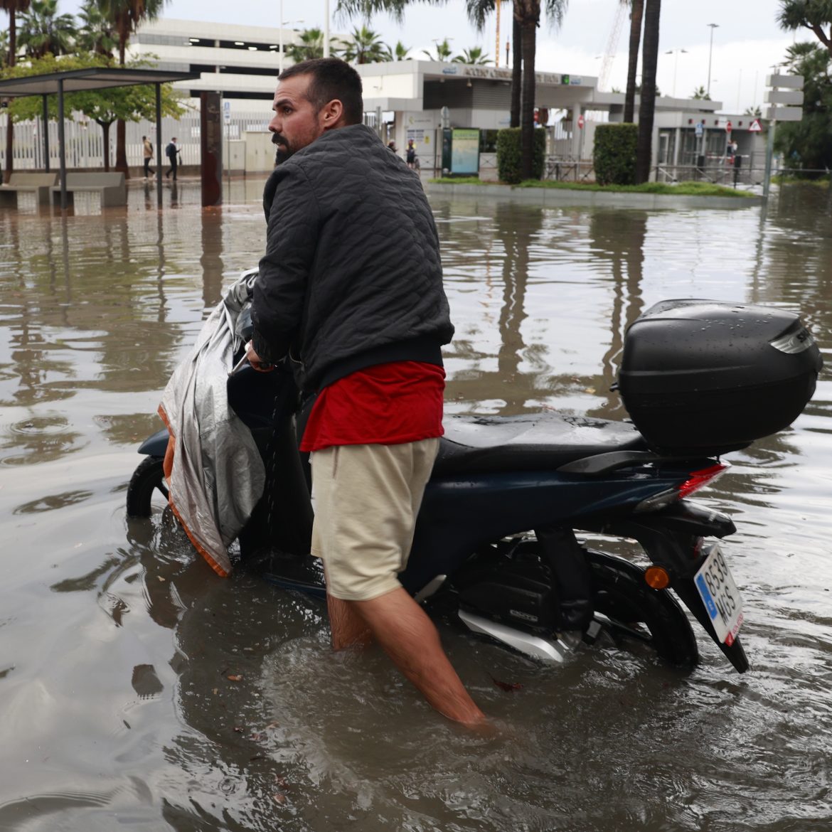 Man loopt met scooter aan de hand door het hoge water