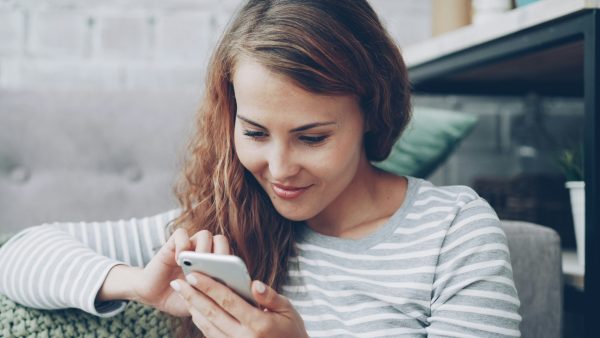 Vrouw kijkt lachend naar scherm van telefoon
