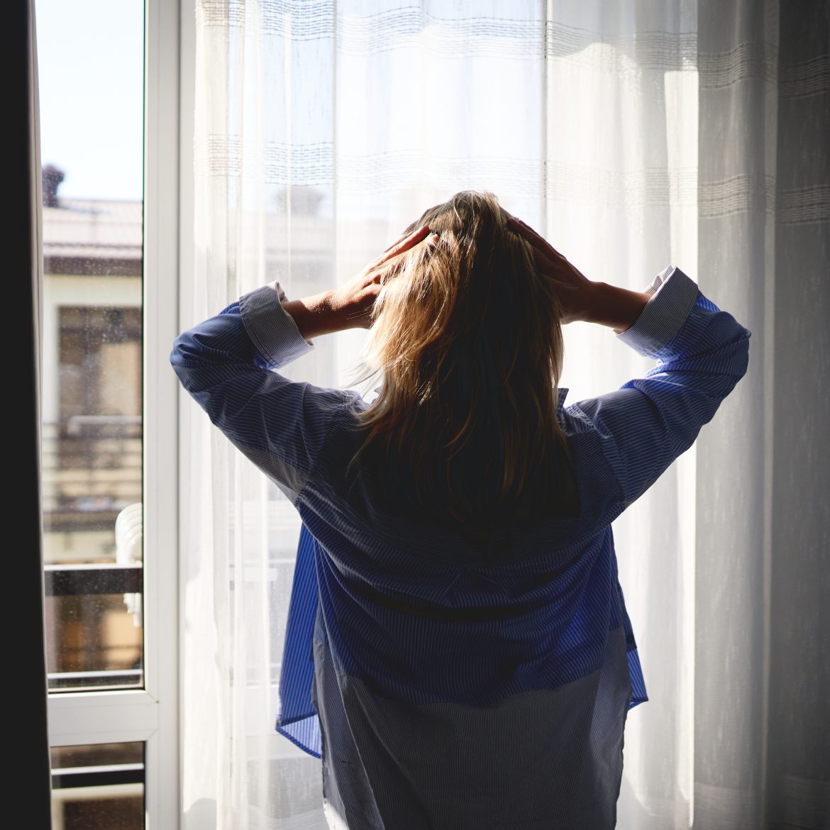 Vrouw staat voor het raam en is in shock want ze heeft meer broers en zussen
